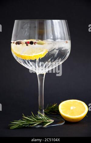 Gin und Tonika mit Zitrone und Rosmarin aus Kristallglas vor schwarzem Hintergrund Stockfoto