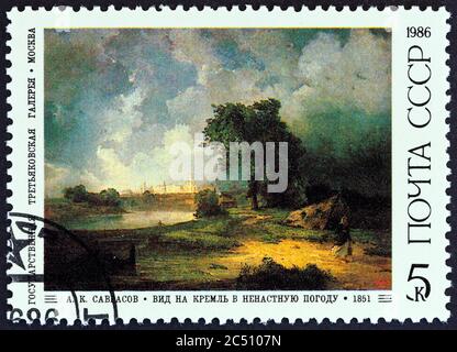 UdSSR - UM 1986: Eine in der UdSSR gedruckte Marke zeigt den Blick auf den Kreml in schlechtem Wetter (1851) von Alexei Savrasov, um 1986. Stockfoto