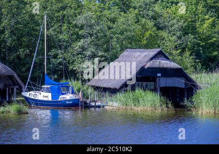 Prerow, Deutschland. Juni 2020. Ein Segelboot legt vor den verbleibenden überdachten Bootshäusern am Prerow-Bach an. Die Hotels, Pensionen und Campingplätze in den Tourismusregionen Mecklenburg-Vorpommerns sind derzeit sehr gut ausgelastet. Quelle: Jens Büttner/dpa-Zentralbild/ZB/dpa/Alamy Live News Stockfoto