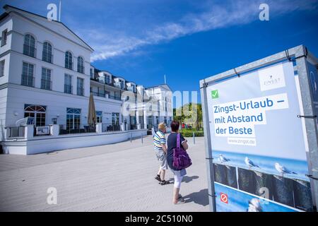 Zingst, Deutschland. Juni 2020. Urlauber gehen an einem Werbeschild der Kurverwaltung vorbei zu den Sicherheitsabständen vor einem Hotel, die als Corona-Schutzmaßnahme vorgeschrieben sind. Die Hotels, Pensionen und Campingplätze in den Tourismusregionen Mecklenburg-Vorpommerns sind derzeit sehr gut ausgelastet. Quelle: Jens Büttner/dpa-Zentralbild/ZB/dpa/Alamy Live News Stockfoto