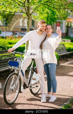 Mann auf dem Fahrrad und Frau mit Smartphone auf dem Bürgersteig stehen Stockfoto