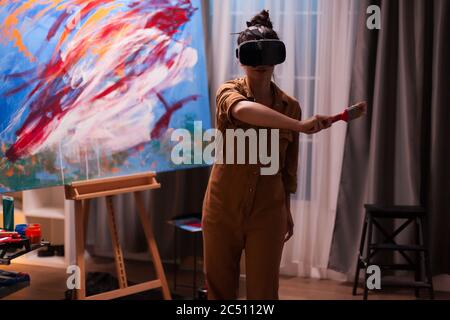 Maler mit Virtual Reality-Headset in Art Studio erstellen ein Meisterwerk. Moderne Kunst malen auf Leinwand, kreative, zeitgenössische und erfolgreiche bildende Kunst Künstler Zeichnung Meisterwerk Stockfoto