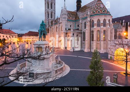 Katholische Matthias Kirche und Statue des Heiligen Stephan auf Fischerbastei in Budapest, Ungarn bei Sonnenaufgang mit Licht von Laternen Stockfoto