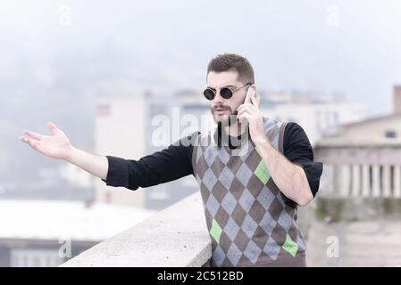 Bärtiger junger Mann, der am Telefon sprach Stockfoto