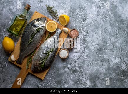 Frischer Fisch dorado oder Seebarsch auf Schneidebrett mit Zutaten Stockfoto