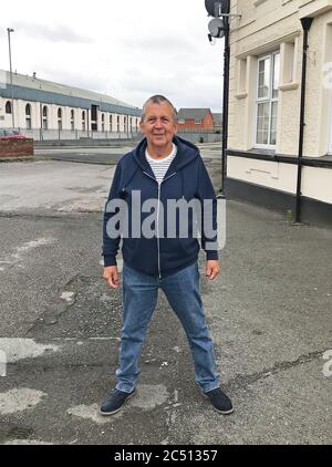 Alan Banks, der Vermieter des Anchor Hotels in der Stadt Saltney, steht einen Fuß auf beiden Seiten der englischen und walisischen Grenze. Stockfoto