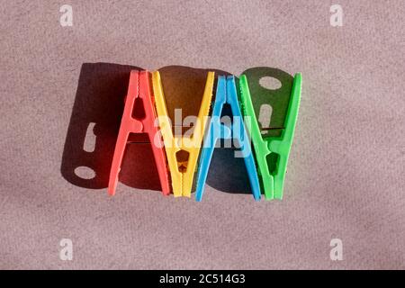 Kreatives Bild für Designer. Rosa, gelbe, rote und blaue Kunststoff-Kleidernadeln auf grauem Hintergrund. Draufsicht und Kopierbereich Stockfoto
