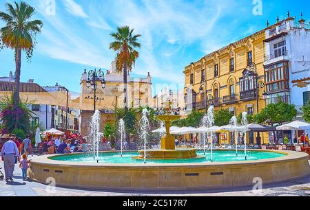 SANLUCAR, SPANIEN - 22. SEPTEMBER 2019: Der überfüllte Platz Plaza del Cabildo, der mit einem malerischen Brunnen geschmückt ist, ist von beliebten Touristenrestaurants gesäumt Stockfoto