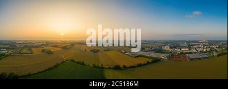Drohnen-Aufnahmen - Blick auf die Felder und ein nahe gelegenes Geschäftsviertel, bedeckt vom Nebel des frühen nassen Morgens. Stockfoto