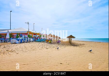 SANLUCAR, SPANIEN - 22. SEPTEMBER 2019: Panorama des Strandes von Calzada mit Sonnenschirmen, Cafés am Fluss und dem sanften Wasser des Guadalquivir Flusses, auf Septem Stockfoto