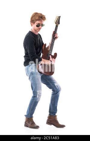 Seitenansicht des roten Haarrockers, der E-Gitarre spielt, mit Sonnenbrille, die nach unten schaut. Ganzkörperhochformat isoliert auf weißem Hintergrund. Stockfoto