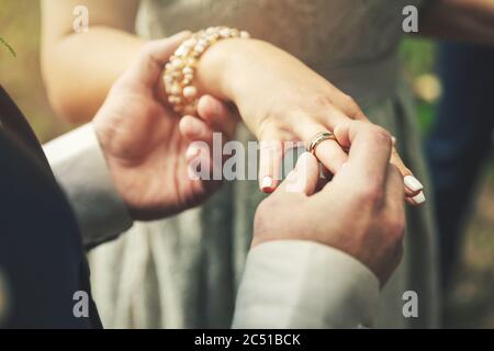 Bräutigam legt Ehering auf Braut Hand Stockfoto