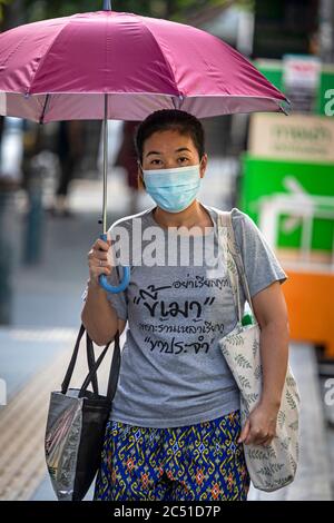 Mädchen mit Gesichtsmaske und Regenschirm während covid 19 Pandemie, Bangkok, Thailand Stockfoto