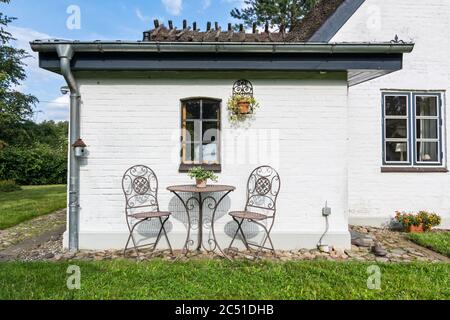 Ruhiger Garten mit zwei Stühlen vor einem weiß getünchten historischen Haus in Norddeutschland Stockfoto