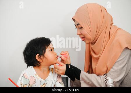 Glücklich Mama und niedlichen Mädchen Spaß machen Make-up zusammen. Mutterschaft und Familienkonzept. Stockfoto