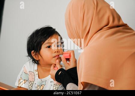 Glücklich Mama und niedlichen Mädchen Spaß machen Make-up zusammen. Mutterschaft und Familienkonzept. Stockfoto