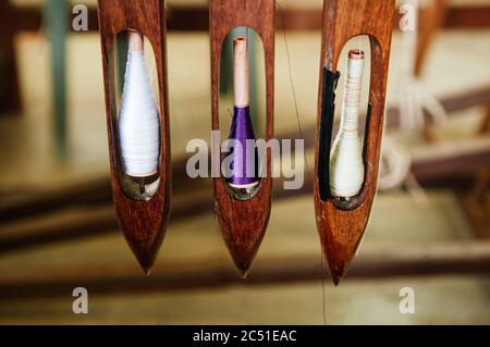 Handgefertigter Thai Stoff, Baumwolle Webstuhl Shuttle mit bunten Faden, Nahaufnahme Textilien Ausrüstungen Details Stockfoto