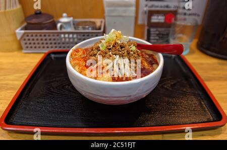 Eine Schüssel mit würzigen japanischen Ramen Nudeln mit einer Vielzahl von Belägen auf einer Holztheke Stockfoto