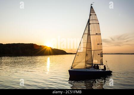 Segelschiff, das während des wunderschönen Sonnenuntergangs in den Hafen segelt Stockfoto