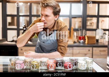 Konditor versucht verschiedene Lebensmittelzusatzstoffe in Form von Belag für Eis an der Theke eines Geschäfts Stockfoto