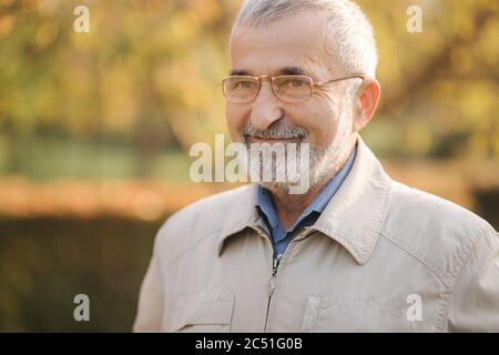 Nahaufnahme von Stattlichen bearder älterer Mann mit Brille. Grauhaariger alter Mann im Park Stockfoto