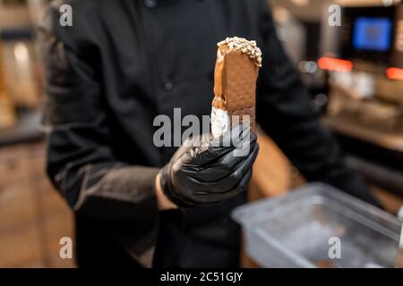 Koch in schwarzer Uniform hält Schokoladeneis, Nahaufnahme Stockfoto