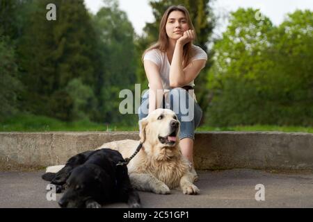 Nachdenkliche Frau hockt neben Hund am Sommertag. Stockfoto