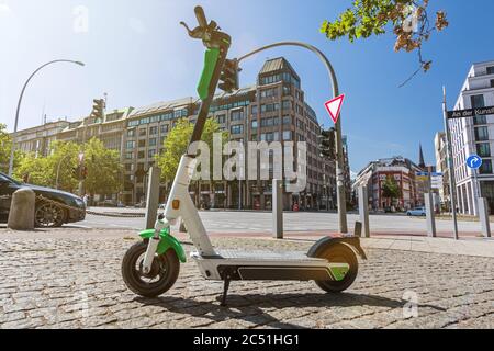 E-Scooter steht auf dem Bürgersteig in einer großen Stadt mit landschaftlich schönen Lichtreflexen Stockfoto