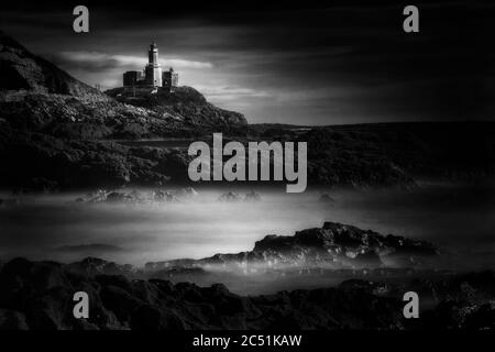 Die Mumbles mit ihrem Leuchtturm von Bracelet Bay auf der Gower Peninsula Wales, UK schwarz-weiß monochrome Bild gesehen Stockfoto