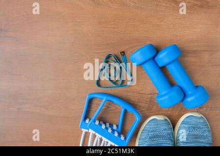 Blaue Farbwerkzeuge für Training, Sport und Aktivität. Zwei Hanteln, kastanienige Expander, Maßband, Turnschuhe und Yoga-Matte zu Hause trainieren. Draufsicht Stockfoto