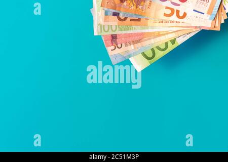 Euro-Banknoten isoliert auf blauem Hintergrund mit weichen Schatten. Euro-Noten in der Ecke auf azurblauem Hintergrund mit Kopierraum. Euro Bargeld mit verschiedenen Werten. Stockfoto