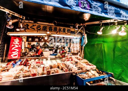 Tokio, Japan - 15. Januar 2010: Am frühen Morgen auf dem Tsukiji Fischmarkt. Arbeiter, der frischen Fisch und Meeresfrüchte auf der Theke ausstellte. Körnungseffekt Stockfoto