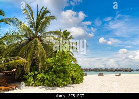 Sonnenliege und Sonnenschirm aus Holz am tropischen Strand der Malediven am Sommertag Stockfoto