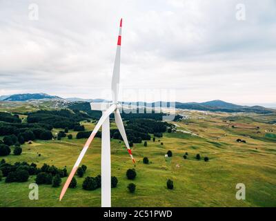 Nahaufnahme von Rotorblättern mit roten Streifen vor einem grünen Wald und Feld. Stockfoto
