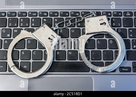 Handschellen, die auf einer Computertastatur liegen und Cyberkriminalität symbolisieren Stockfoto