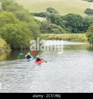 Zwei Kanufahrerinnen/Kajakfahrerinnen paddeln auf dem Fluss Fowey in Lostwihiel in Cornwall. In Richtung Downstream. Stockfoto