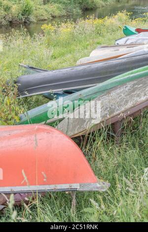 Gruppe von umgedrehten Kanus und Kajaks auf Kajak-Startplatz auf dem Fluss Fowey in Lostwihiel, Cornwall. Für das Herumwirren auf dem Fluss, Flusssport Stockfoto