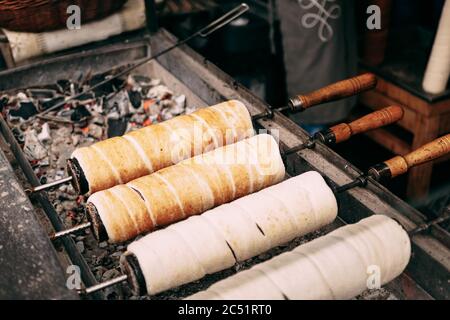 Budapest Ungarische Süßigkeiten Kurtoskalacs - Schornsteingebäck Spit Kuchen auf dem Weihnachtsmarkt. Traditionelle saisonale Winterfreude mit Milchbrot und Stockfoto