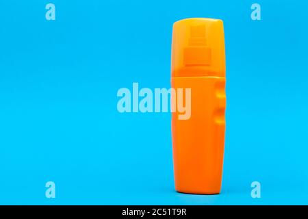 Orange Plastikflasche Suntan Creme Seitenansicht auf einem blauen Hintergrund mit Kopierraum. Stockfoto