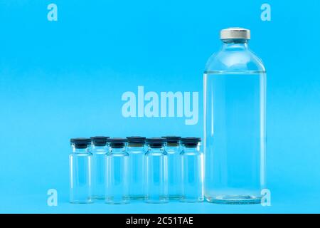 Glasflaschen mit Medikamenten für Impfstoffe auf blauem Hintergrund auf einem medizinischen Thema mit einem Kopierraum. Stockfoto