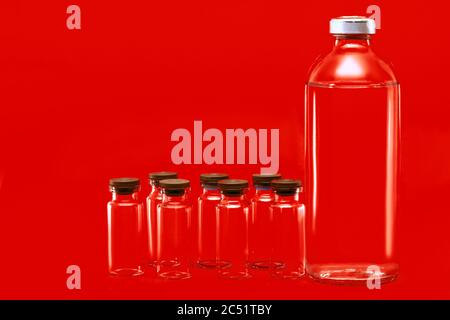 Glasflaschen mit Medikamenten für gefährliche Viruserkrankungen Impfstoff auf einem roten Hintergrund auf einem medizinischen Thema mit einem Kopierraum. Stockfoto