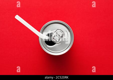 Aluminium-Getränke- oder Getränkedose mit weißem Stroh auf rotem Hintergrund. Getränke trinken. Ansicht von oben oder von oben. Stockfoto