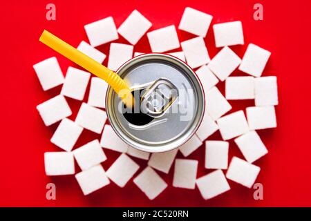 Cola oder Sodadose auf Zuckerwürfeln auf rotem Hintergrund. Ungesunde Ernährung und Risiko von Diabetes oder Adipositas Konzept. Ansicht von oben. Stockfoto