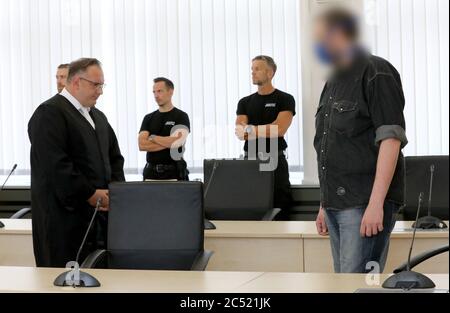 30. Juni 2020, Mecklenburg-Vorpommern, Rostock: Rechtsanwalt Jens Otte (l), Rechtsanwalt, wartet mit dem Angeklagten im Prozess auf den Doppelmord seiner Eltern im Saal des Landgerichts auf den Beginn des Prozesses, im Hintergrund Justizpersonal. Der Angeklagte soll seinen schlafenden Vater mit einem Schlosserhammer wiederholt auf den Kopf geschlagen und ihn 21 Mal mit einem Küchenmesser gestochen haben. Danach soll er seine Mutter mit 41 Stichen getötet haben. Der arbeitslose Mann lebte bei seinen Eltern. Foto: Bernd Wüstneck/dpa-Zentralbild/dpa - ACHTUNG: Beklagter war Stockfoto