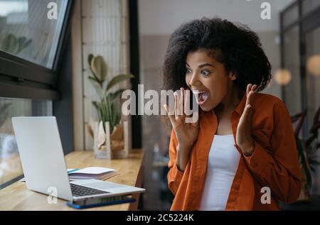 Aufgeregt afroamerikanischen Frau gewinnen online Lotterie, Feier Erfolg. Glückliche emotionale Frau mit Laptop-Computer für Online-Shopping Stockfoto
