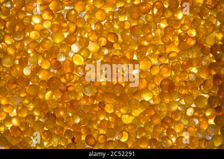 Nahaufnahme des Orangensilicagels. Goldene, durchscheinende Perlen mit glänzendem Licht Stockfoto