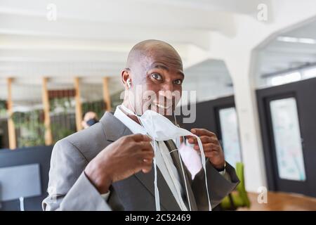 Afrikanischer Geschäftsmann fastet Gesichtsmaske im Büro wegen Covid-19 und Coronavirus Pandemie Stockfoto