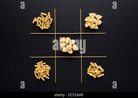 TIC tac Toe Spiel mit Pasta auf schwarzem Hintergrund. Kochen Wahl oder Entscheidung unter den Alternativen. Stockfoto