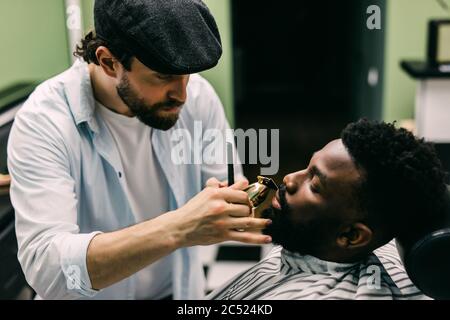 Profilansicht des ruhigen Mannes, der im Komfortstuhl im Friseurladen sitzt. Stockfoto