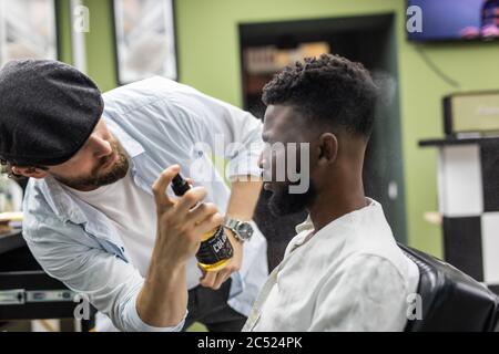 Junge schwarze Mann Kunde erhielt neue Frisur in Friseurladen. Stockfoto